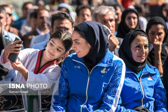 عکس منتخب سال - ۶ شهریور- دختربچه ورزشکار با کیمیا علیزاده برنده مدال المپیک در مراسمی‌ که برای تقدیر از او برپا شده عکس سلفی می‌گیرد.